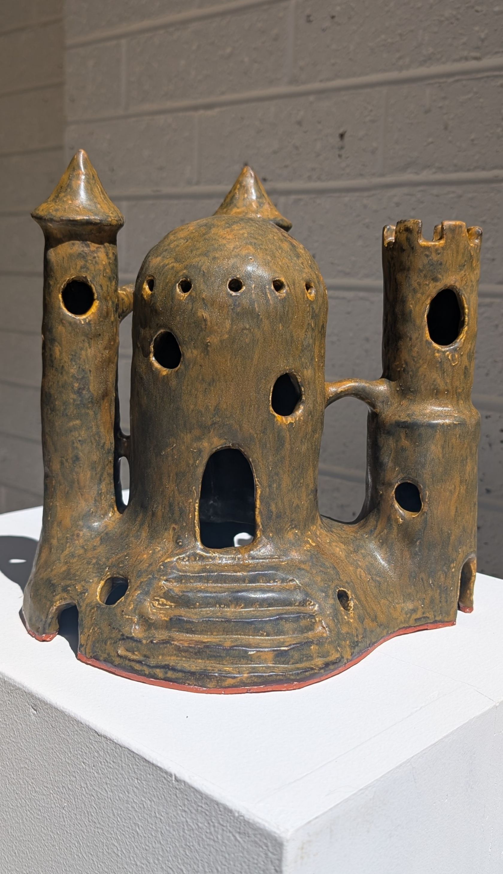 Ceramic castle-shaped object on a white surface with a gray background